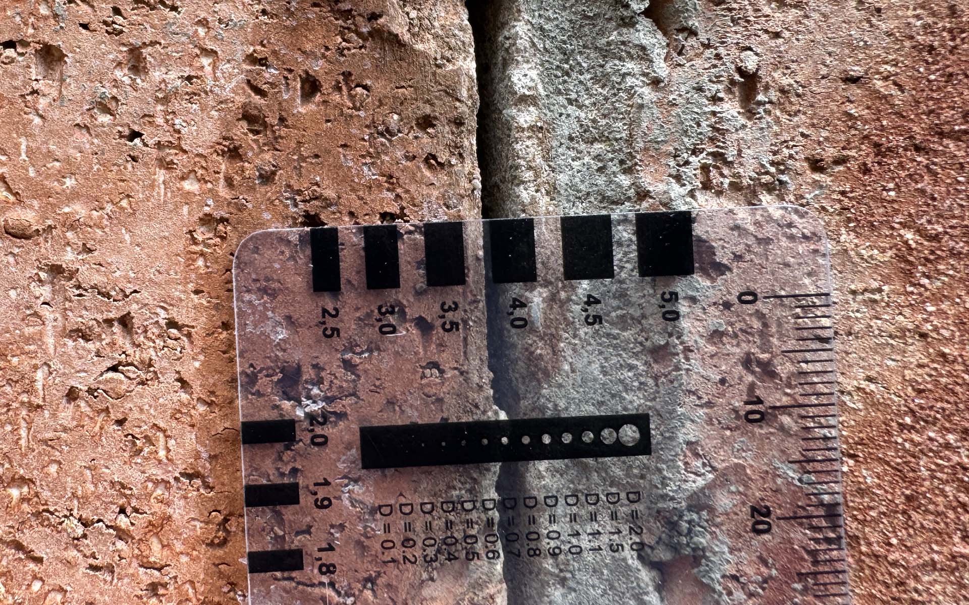 Measured masonry crack using crack gauge to document crack width in brick veneer
