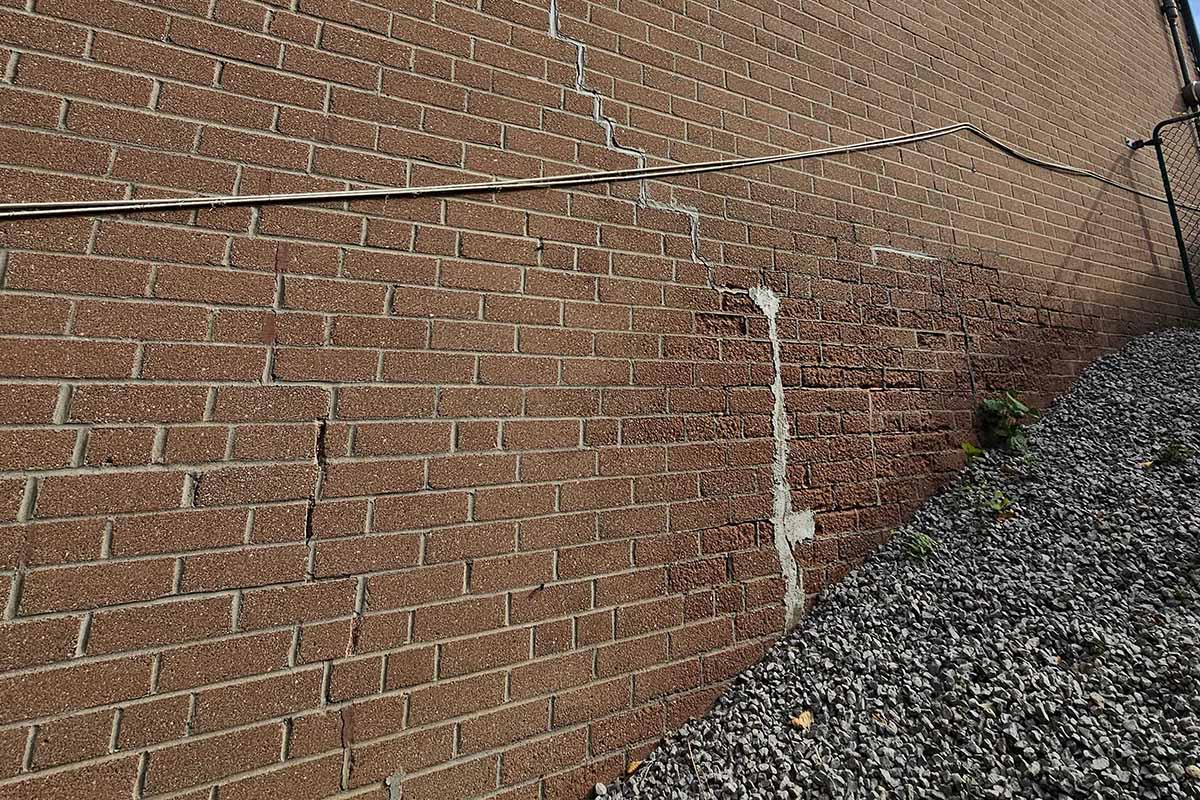 Vertical cracking and moisture staining in brick veneer wall during structural inspection