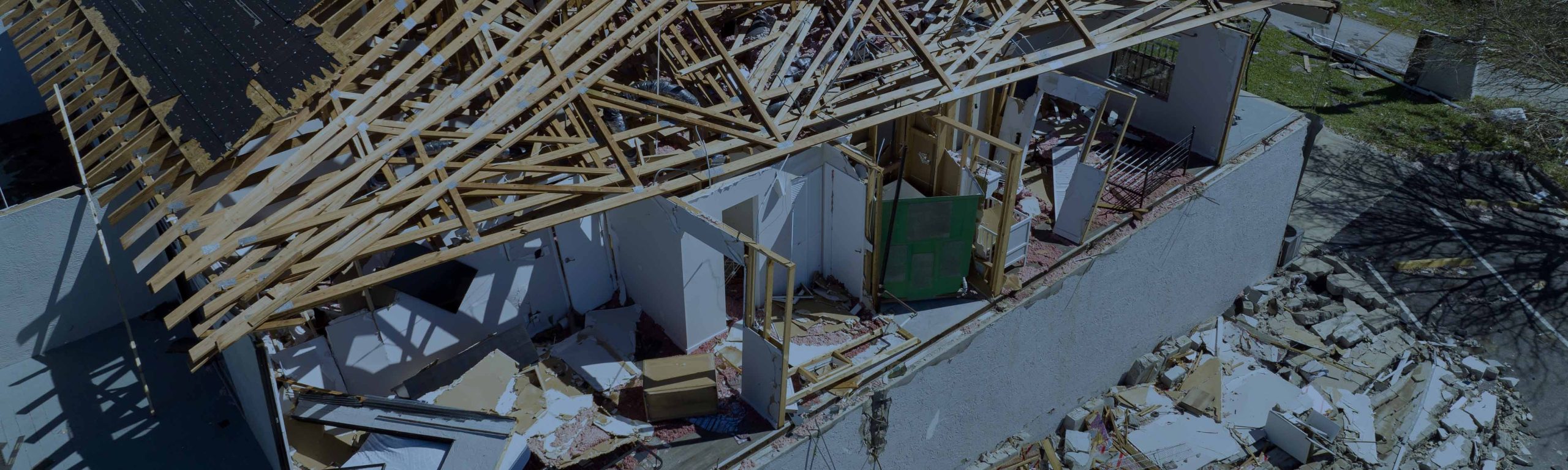 Partially collapsed residential building with exposed roof framing and structural damage