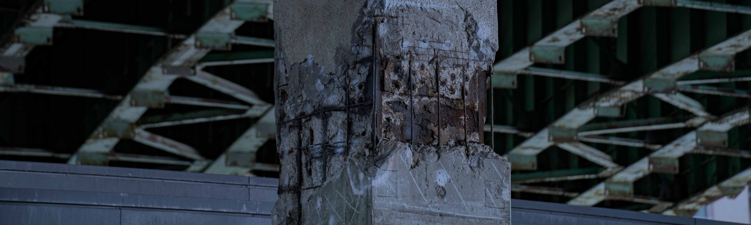 Concrete column with spalled cover and exposed corroded reinforcing steel during structural inspection