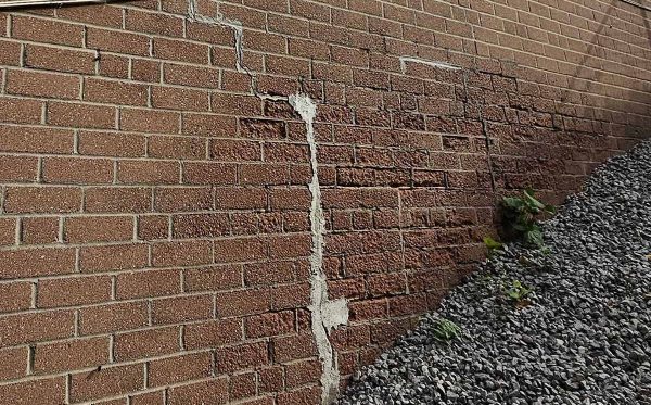 Forensic engineering photo of stair-step cracking in a masonry wall caused by building envelope failure and structural settlement.