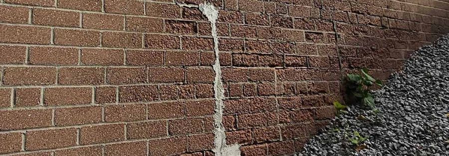 Forensic engineering photo of stair-step cracking in a masonry wall caused by building envelope failure and structural settlement.
