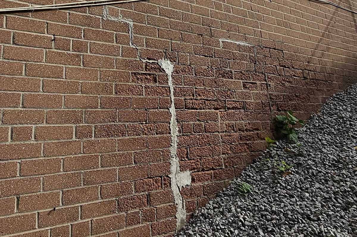 Forensic engineering photo of stair-step cracking in a masonry wall caused by building envelope failure and structural settlement.
