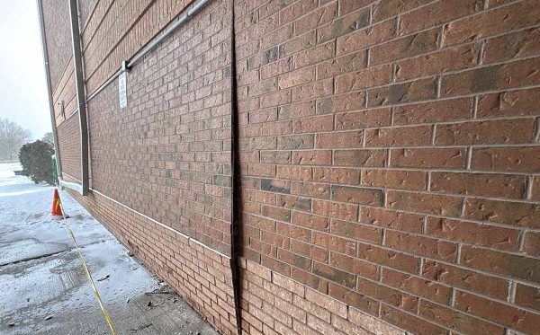 Bulging brick veneer wall between vertical joints showing outward displacement