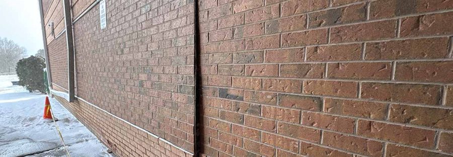 Bulging brick veneer wall between vertical joints showing outward displacement