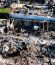Aerial view of a residential structure fire site with exposed concrete foundation walls and debris.