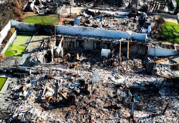 Aerial view of a residential structure fire site with exposed concrete foundation walls and debris.