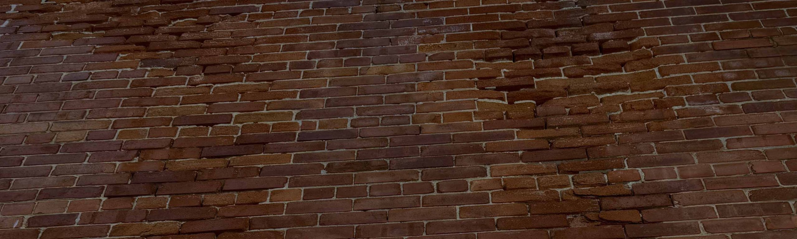 Damaged brick masonry wall showing cracking and outward displacement during structural assessment